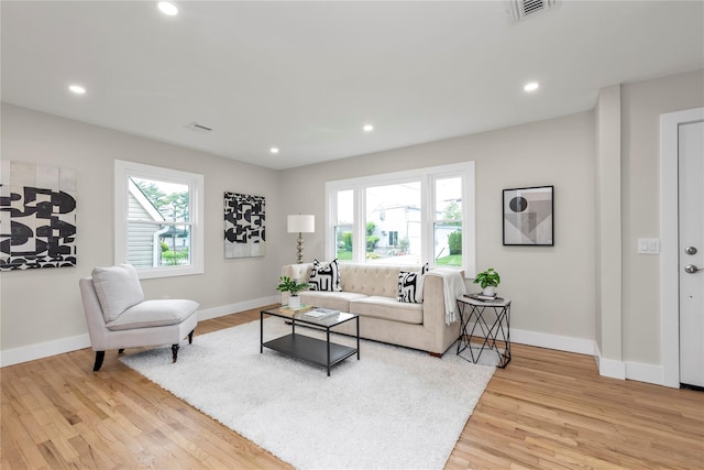 living area with a wealth of natural light, visible vents, light wood-style flooring, and baseboards