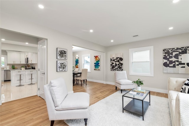 living area with light wood-style floors, visible vents, and recessed lighting
