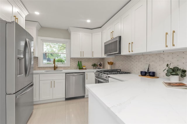 kitchen featuring a sink, stainless steel appliances, white cabinets, light stone countertops, and tasteful backsplash
