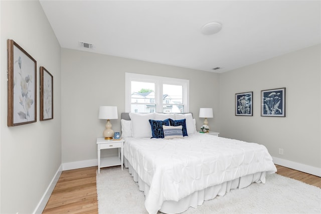 bedroom featuring baseboards, light wood-style flooring, and visible vents