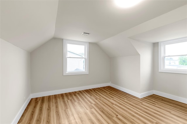bonus room featuring vaulted ceiling, visible vents, light wood-style flooring, and baseboards