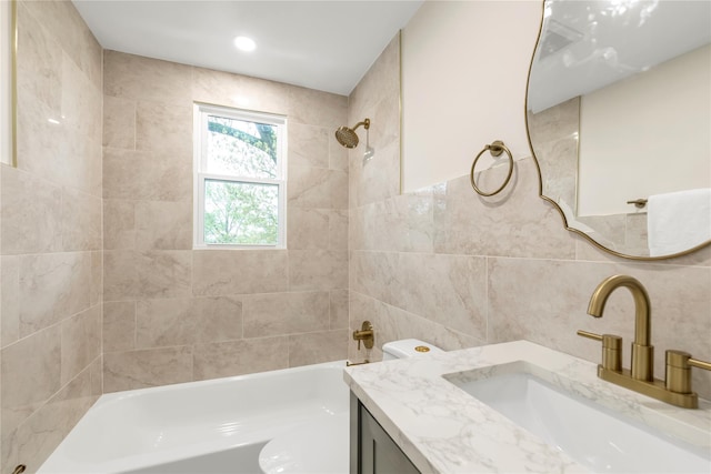 full bathroom with tile walls, vanity, and shower / washtub combination