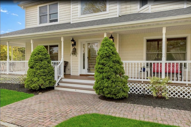 view of exterior entry featuring a porch and roof with shingles