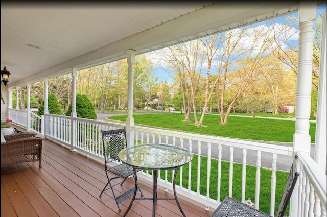 wooden deck featuring covered porch and a yard