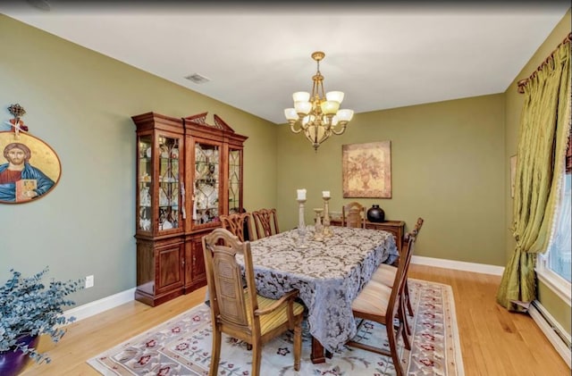 dining room featuring baseboards, an inviting chandelier, baseboard heating, and light wood-type flooring