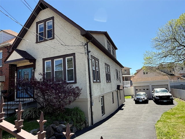 view of side of property featuring an outdoor structure, stucco siding, fence, and a wall mounted air conditioner