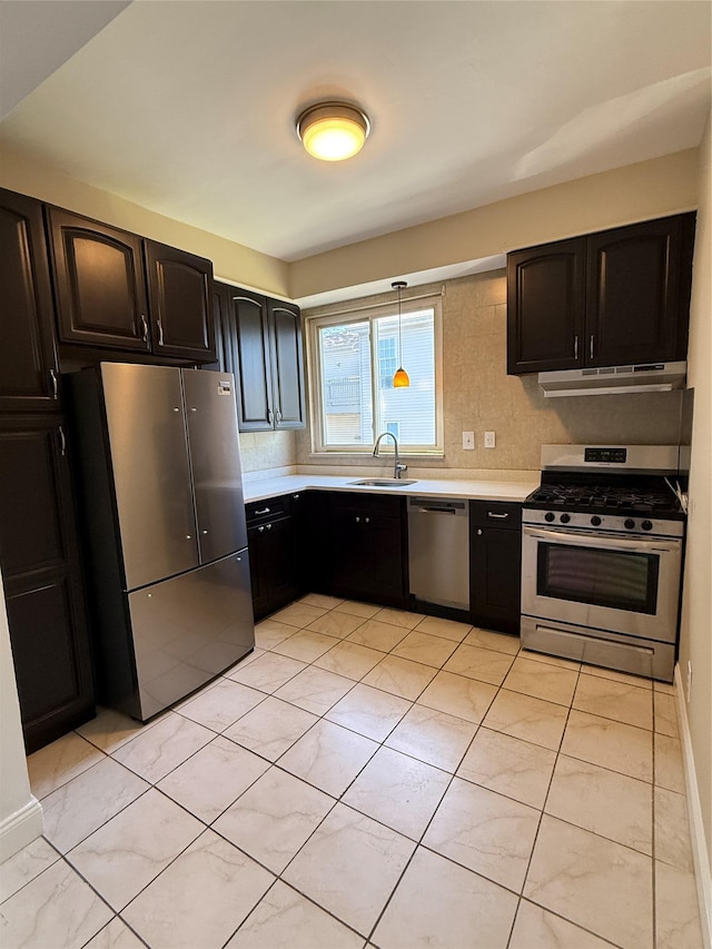 kitchen featuring appliances with stainless steel finishes, a sink, light countertops, decorative light fixtures, and under cabinet range hood