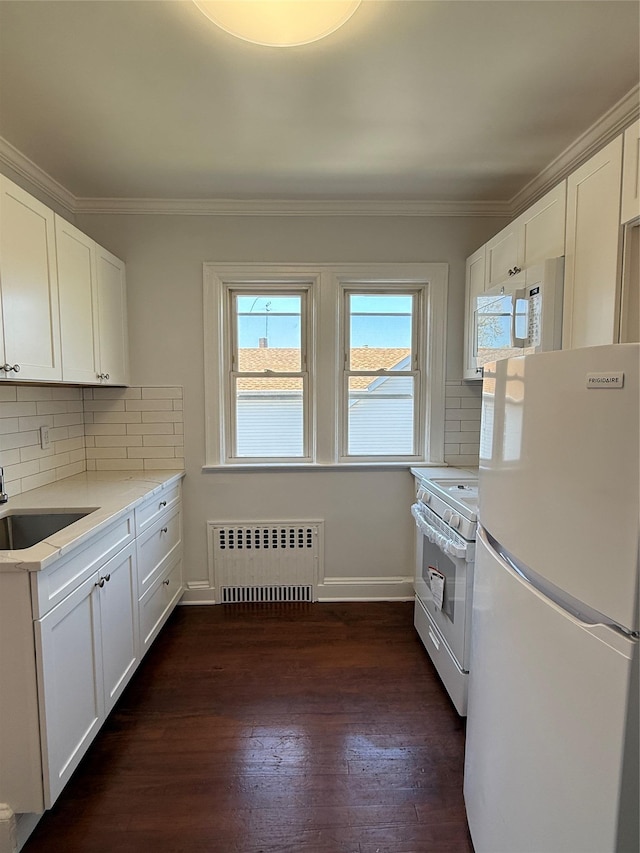 kitchen featuring white appliances, plenty of natural light, a sink, and radiator