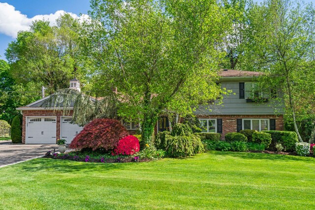 view of front of property featuring brick siding, concrete driveway, a front yard, and a garage