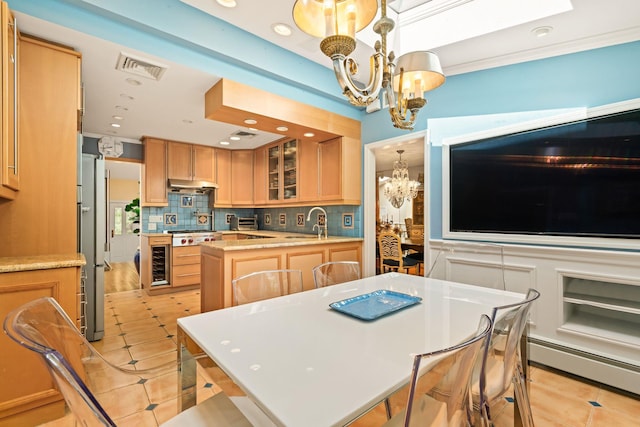 kitchen featuring a chandelier, a sink, a baseboard heating unit, light brown cabinets, and under cabinet range hood