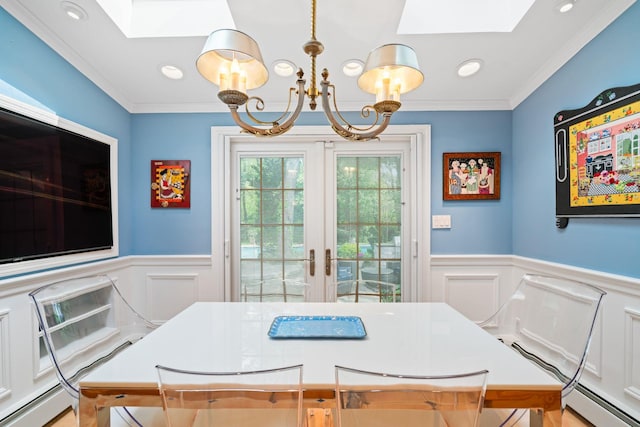 dining space featuring a skylight, wainscoting, a decorative wall, a baseboard heating unit, and a chandelier