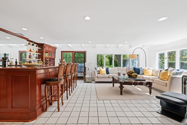 living room featuring a bar, recessed lighting, light tile patterned floors, healthy amount of natural light, and beamed ceiling