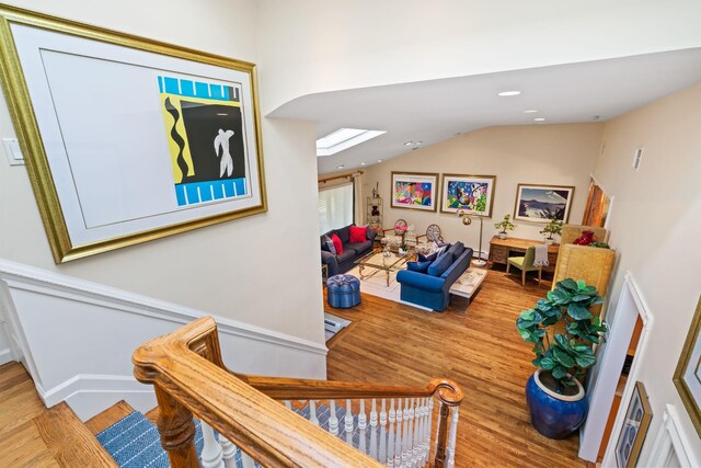 stairway featuring wood finished floors, lofted ceiling, a skylight, and recessed lighting