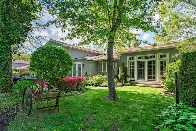 back of property with french doors, a yard, and a chimney