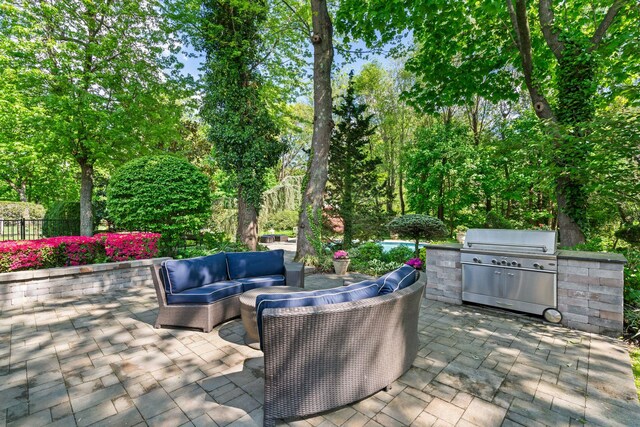 view of patio / terrace with area for grilling, outdoor lounge area, and view of wooded area