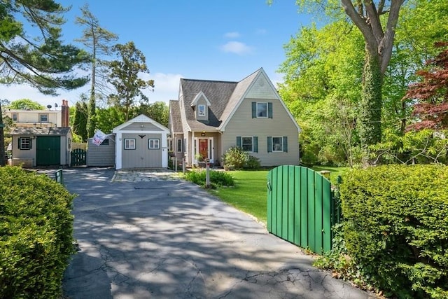 cape cod house featuring a storage shed and an outbuilding