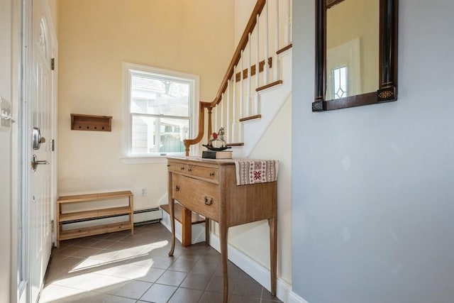 entryway featuring a towering ceiling, tile patterned flooring, baseboard heating, stairway, and baseboards