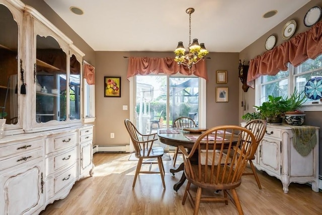 dining space with a notable chandelier, a baseboard radiator, and light wood-type flooring