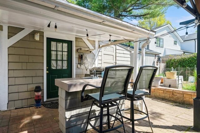view of patio with fence, outdoor dry bar, and a sink
