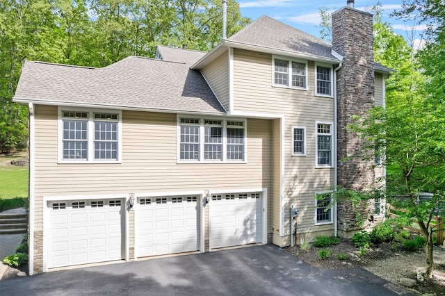 30 Warwick Lake Pkwy, Warwick, NY 10990 - view of side of property featuring asphalt driveway, a garage, a chimney, and a shingled roof
