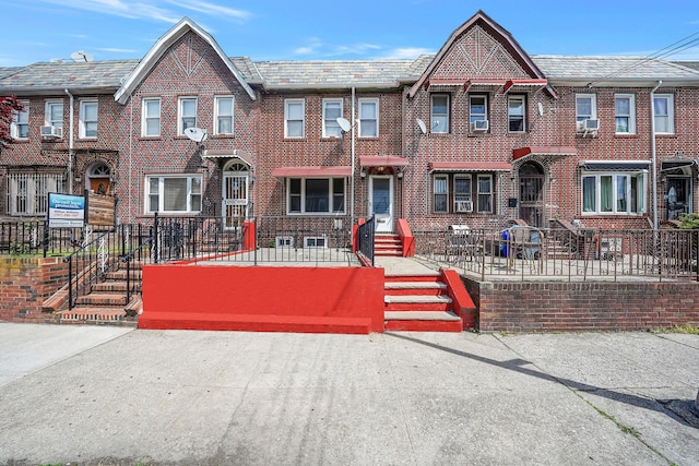 townhome / multi-family property featuring brick siding, cooling unit, and a fenced front yard
