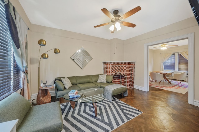 living room featuring a brick fireplace, a ceiling fan, and baseboards
