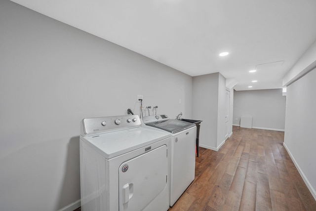 laundry area with laundry area, washing machine and dryer, light wood-type flooring, baseboards, and recessed lighting