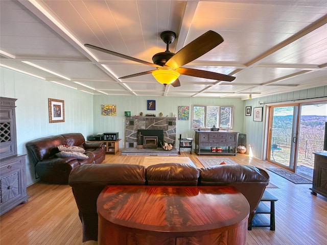living room with ceiling fan, coffered ceiling, a wood stove, and hardwood / wood-style floors