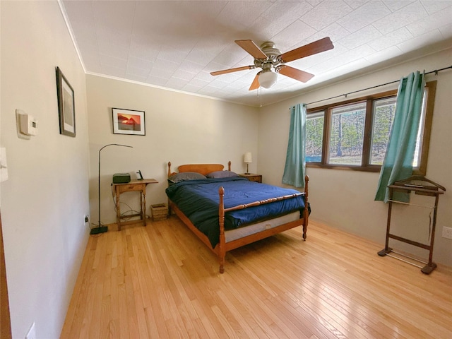 bedroom featuring crown molding, a ceiling fan, and light wood finished floors