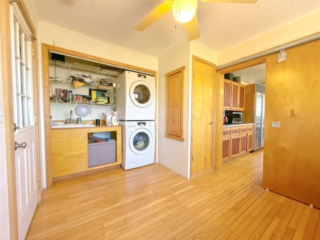 laundry area with crown molding, stacked washer and dryer, laundry area, and a sink