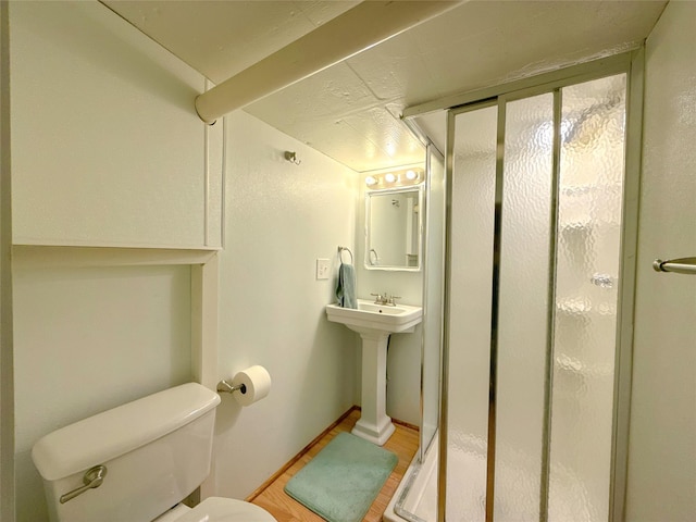 full bath featuring a stall shower, wood finished floors, and toilet