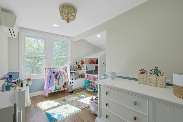 playroom with a wall unit AC, light wood-style floors, lofted ceiling, recessed lighting, and baseboards