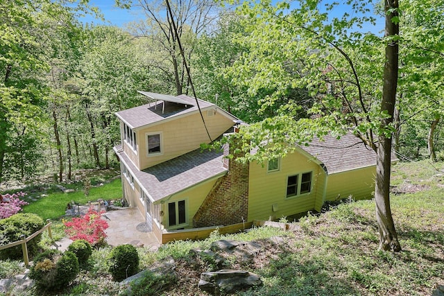 view of side of property with a patio and a shingled roof