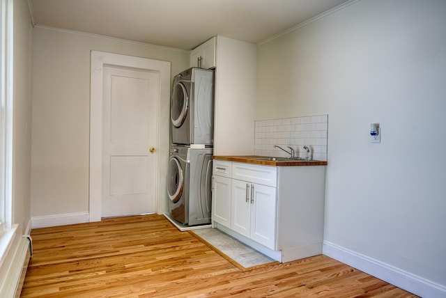 71 Lenox Ave, Congers, NY 10920 - laundry room featuring stacked washer / drying machine, cabinet space, light wood finished floors, ornamental molding, and baseboards