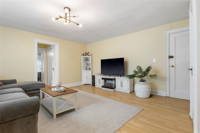 living area with an inviting chandelier, baseboards, and light wood finished floors