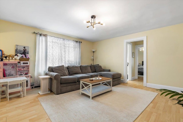 living room with an inviting chandelier, baseboards, and light wood finished floors