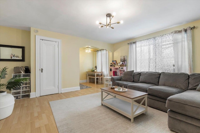 living area with baseboards, wood finished floors, and a notable chandelier