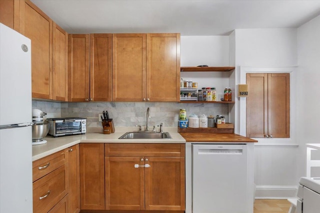 kitchen featuring a sink, a toaster, backsplash, and white appliances