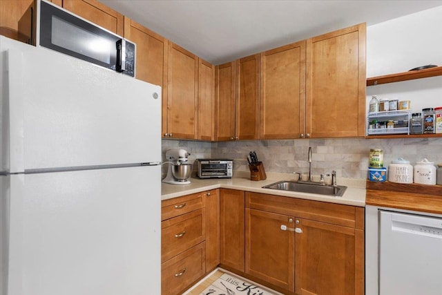 kitchen with a toaster, white appliances, light countertops, a sink, and backsplash