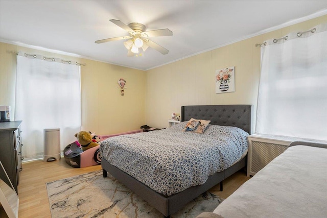 bedroom featuring crown molding, a ceiling fan, light wood-style flooring, and radiator