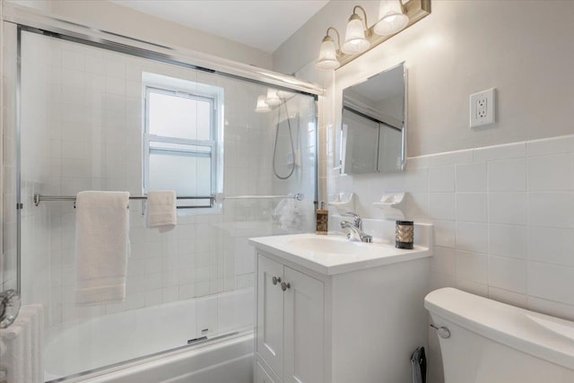 full bathroom featuring tile walls, bath / shower combo with glass door, vanity, toilet, and radiator