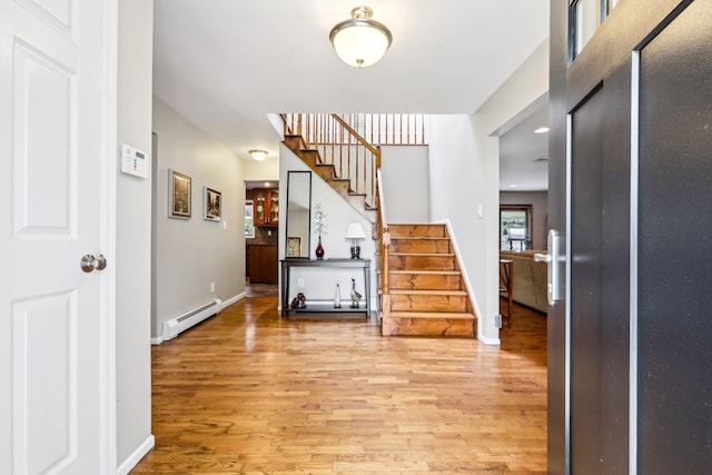 entryway with stairs, baseboards, baseboard heating, and light wood finished floors