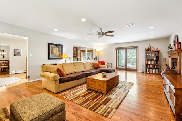 living area featuring light wood-style floors, a baseboard heating unit, recessed lighting, and visible vents