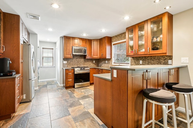 kitchen with backsplash, stainless steel appliances, baseboards, and a peninsula