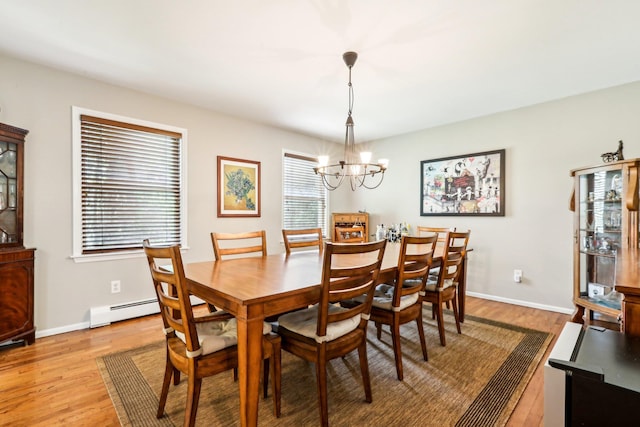 dining area featuring baseboards, a baseboard heating unit, light wood-type flooring, and a chandelier