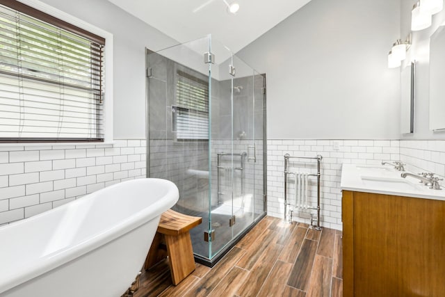 full bath featuring tile walls, a soaking tub, a shower stall, and wood finished floors