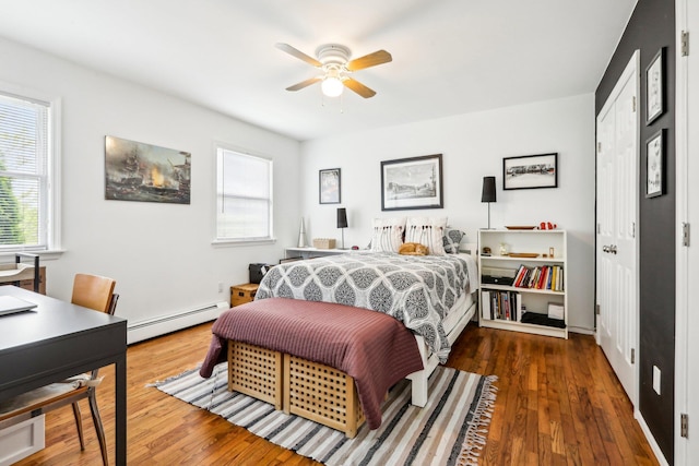 bedroom with a baseboard radiator, hardwood / wood-style floors, and multiple windows
