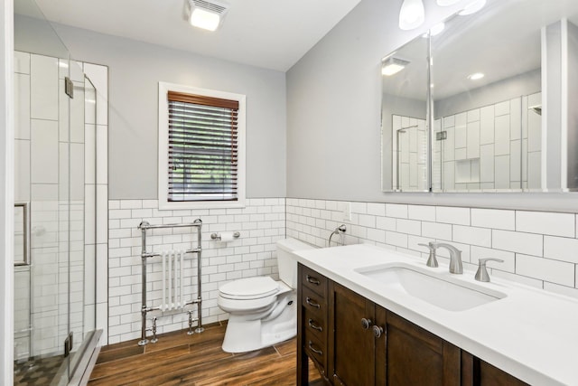 full bathroom featuring vanity, toilet, tile walls, wood finished floors, and a stall shower