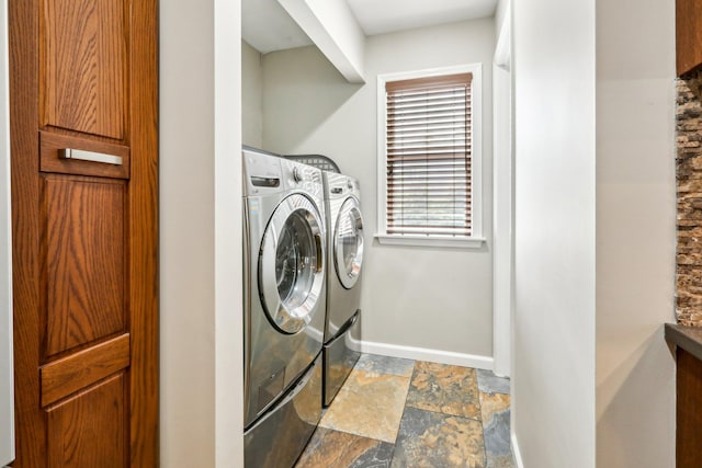 laundry room featuring baseboards, laundry area, stone finish flooring, and independent washer and dryer