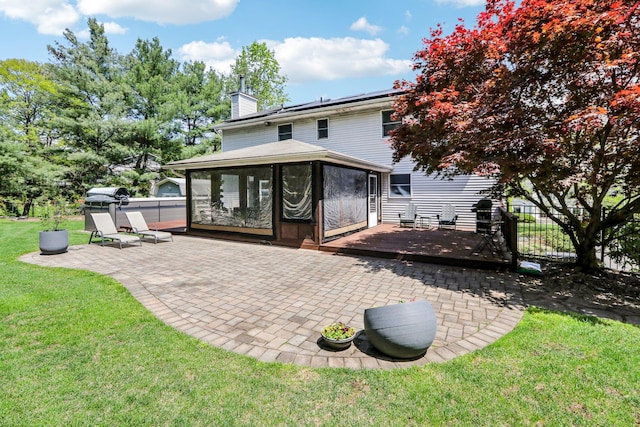 back of property featuring fence, a chimney, a sunroom, a patio area, and a yard